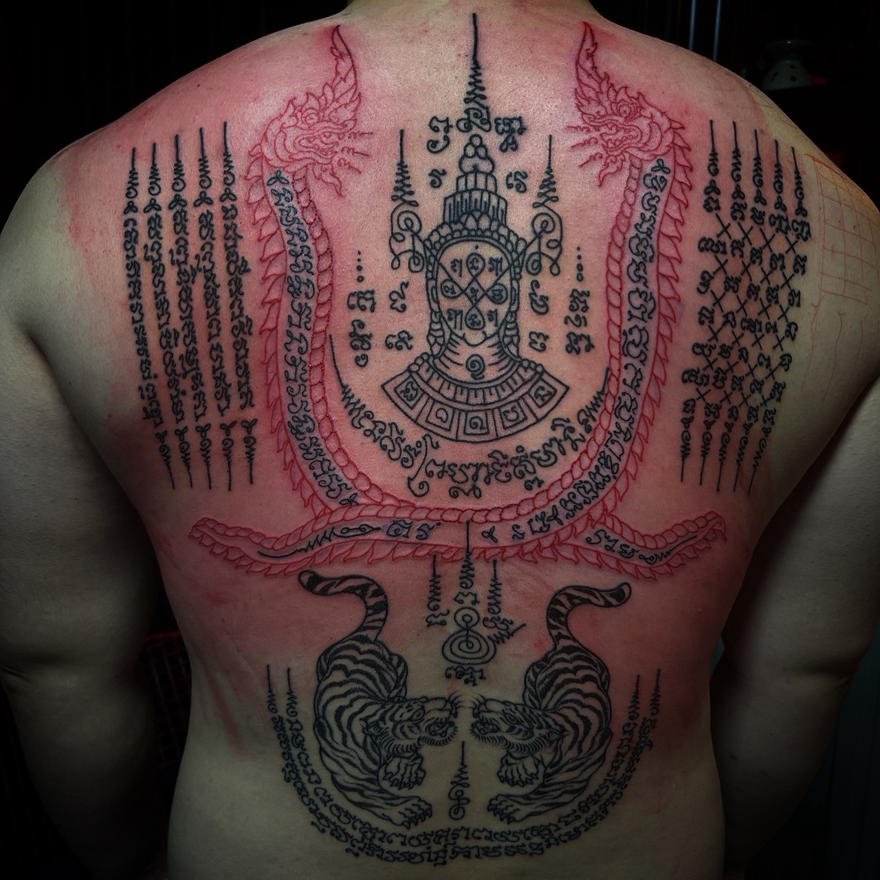 Red and black Sak Yant back tattoo