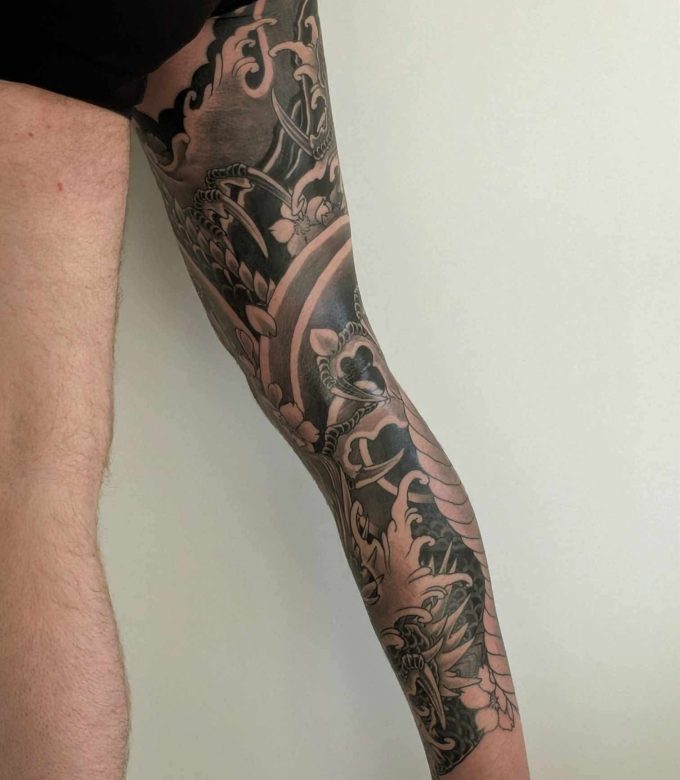 Japanese style leg sleeve tattoo with dynamic flow and black and grey shading, custom design by Dragonking Tattoo Pattaya