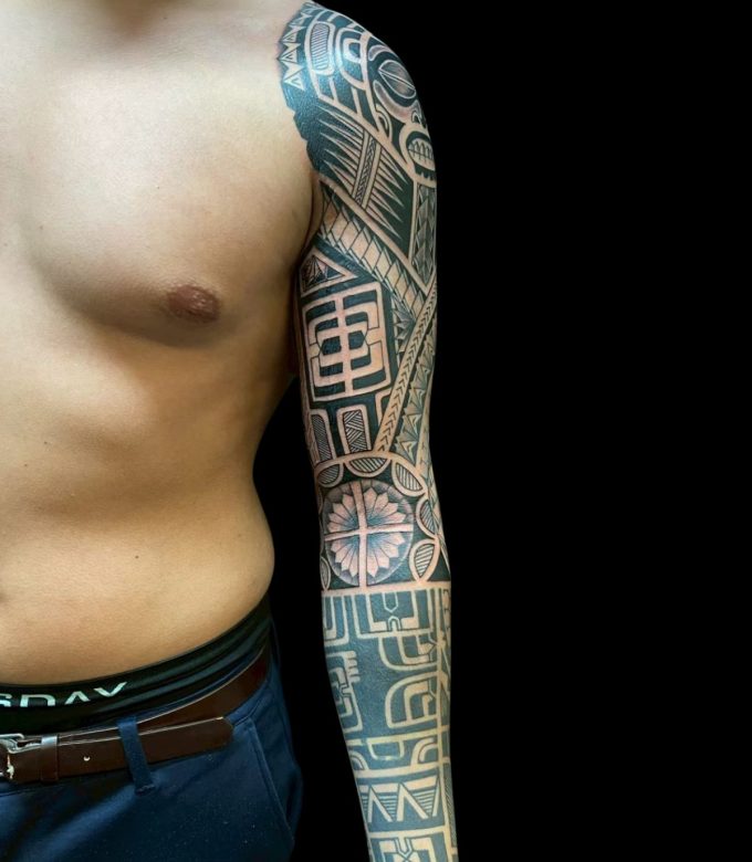 Custom Polynesian full sleeve tattoo with geometric blackwork patterns from shoulder to forearm at Dragon King Tattoo Pattaya