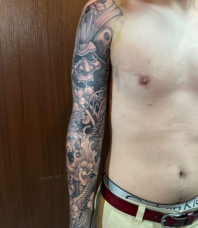 Black and grey Japanese full sleeve tattoo in progress, custom freehand design with dragon and traditional elements by Dragonking Tattoo Pattaya
