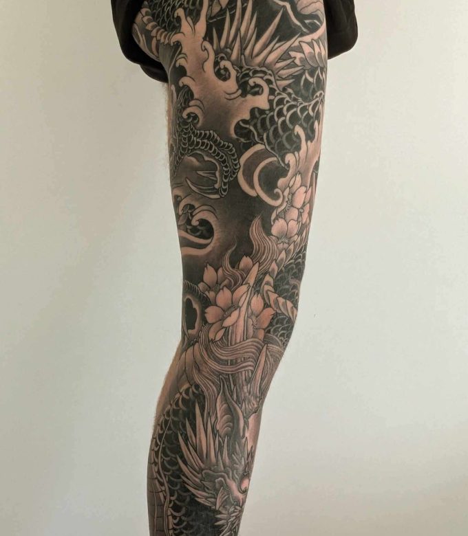 Japanese dragon full leg sleeve tattoo with floral design in black and grey by Dragonking Tattoo Pattaya