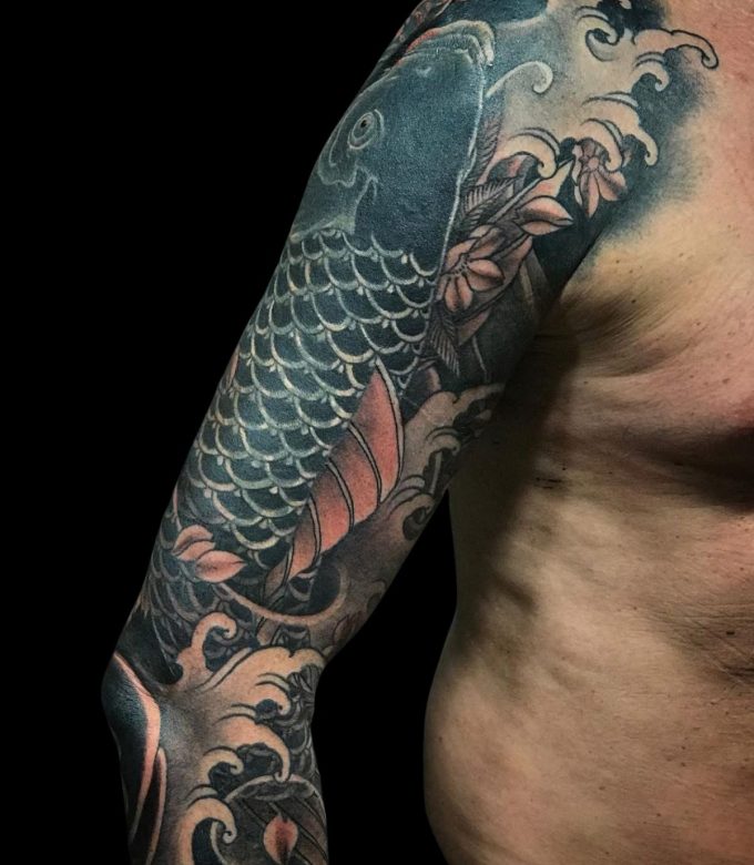 Japanese Koi fish tattoo with waves and cherry blossoms on upper arm